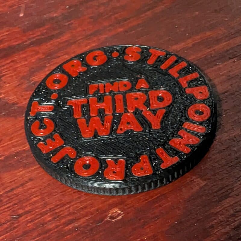 The back of the StillPoint coin, with the words FIND A THIRD WAY and STILLPOINTPROJECT.ORG around the rim